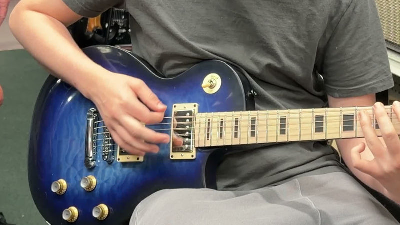 The builder playing the blue burst electric guitar he assembled from a kit