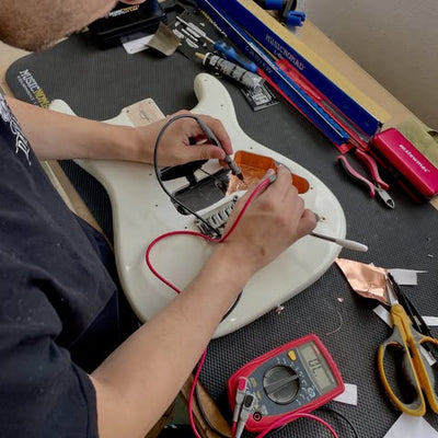 Montagem da eletrónica no corpo de uma guitarra elétrica, testada com multímetro, na Academia Clínica da Guitarra em Pombal