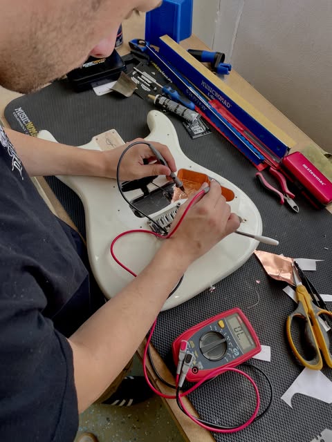 Montagem da eletrónica no corpo de uma guitarra elétrica, testada com multímetro, na Academia Clínica da Guitarra em Pombal