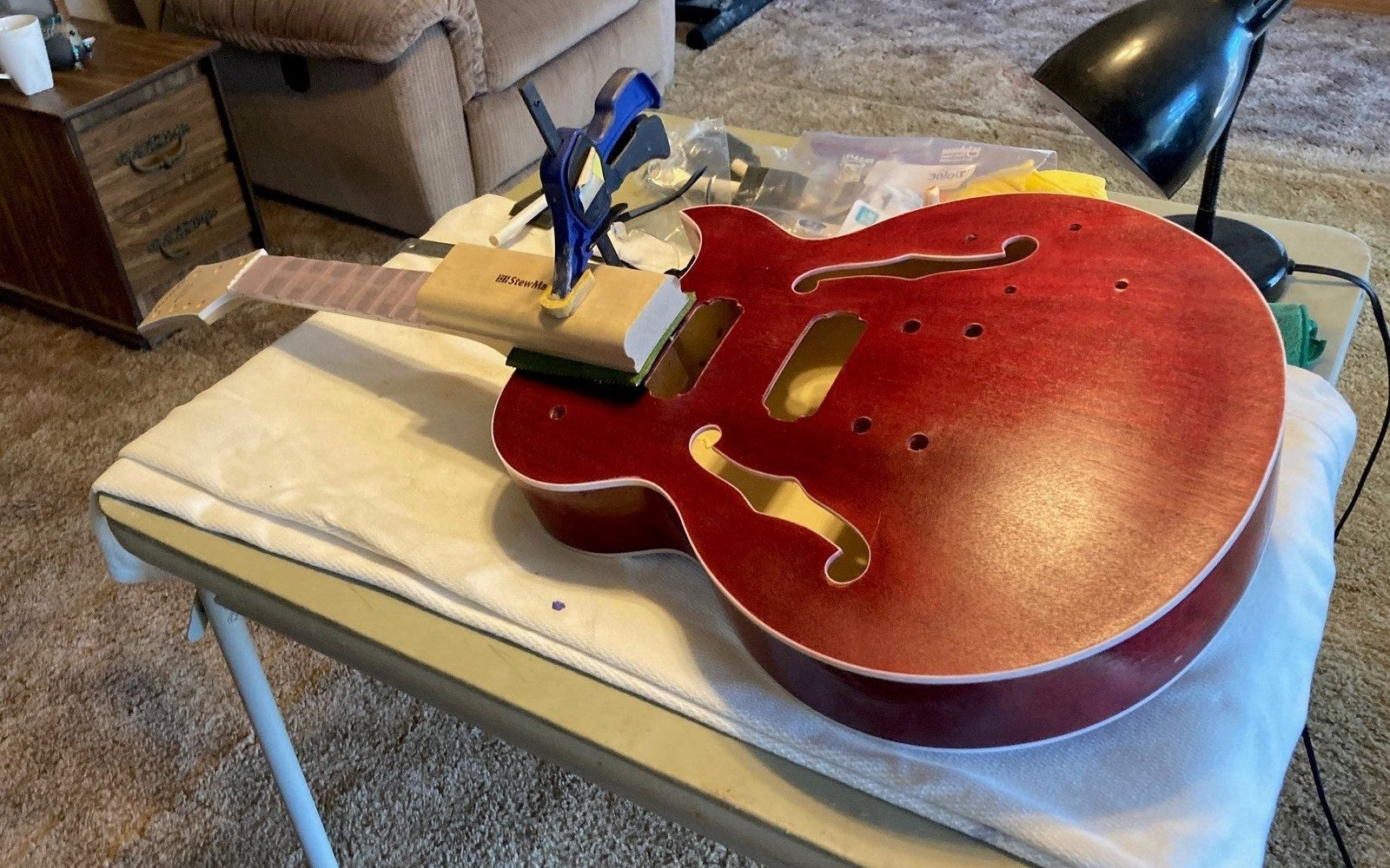 Byron Stafford's red semi-hollow guitar body on the bench with its set neck clamped into the joint