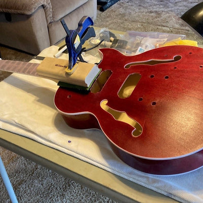 Byron Stafford's red semi-hollow guitar body on the bench with its set neck clamped into the joint