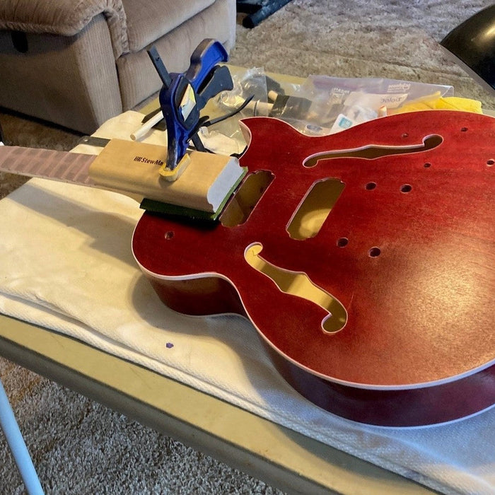 Byron Stafford's red semi-hollow guitar body on the bench with its set neck clamped into the joint