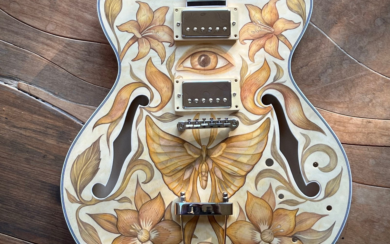 Semi-hollow guitar body drawn in colored pencil: lilies, a moth, and an open eye between the humbuckers