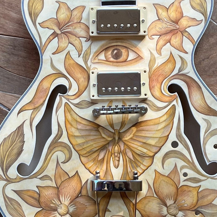 Semi-hollow guitar body drawn in colored pencil: lilies, a moth, and an open eye between the humbuckers