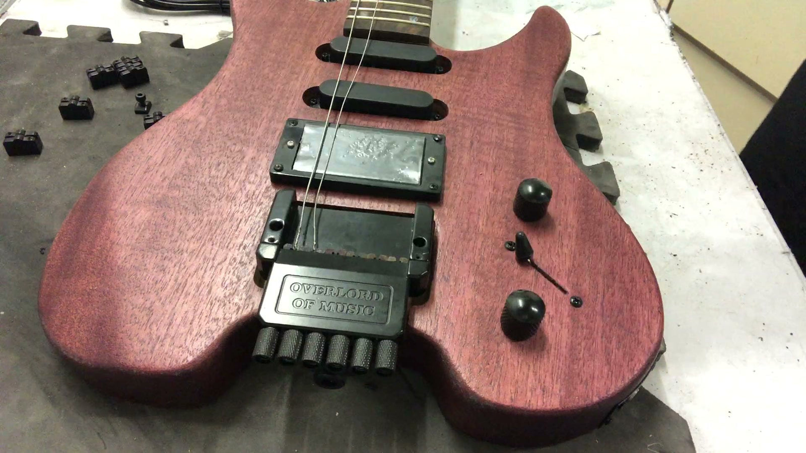Assembled headless electric guitar kit body in a stained mahogany finish, showing the humbucker and two single-coil pickups, the volume and tone knobs, and the headless bridge with its six thumbwheel tuners