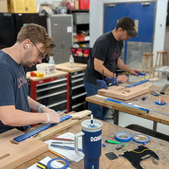 Builders sanding and shaping guitar bodies during the April 2026 Fairfax workshop with luthier Kalimar Maia.