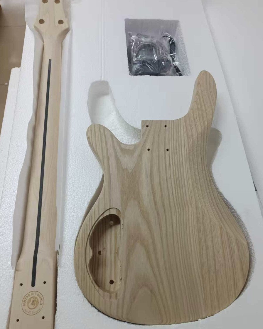 Back of an unfinished ash bass body showing open straight grain, with the control cavity routed