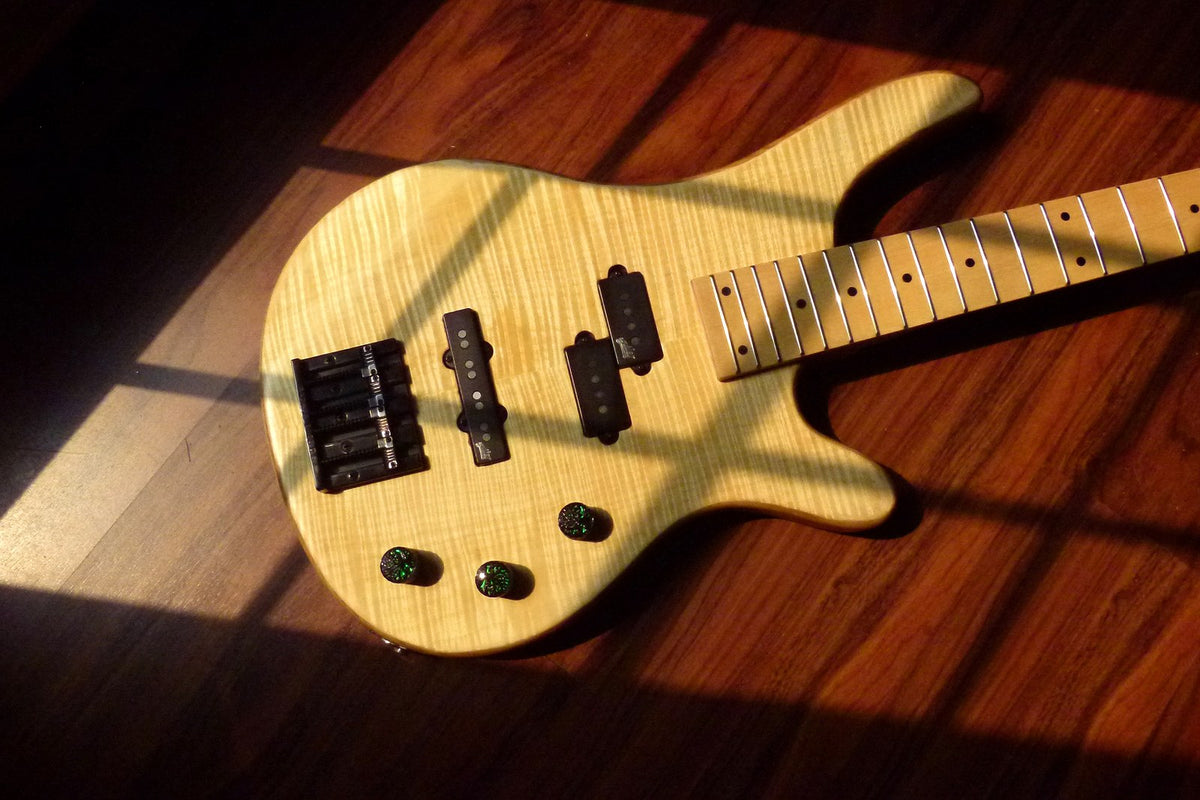 Finished natural bass with black high-mass bridge, split and single-coil pickups and three control knobs on flamed maple