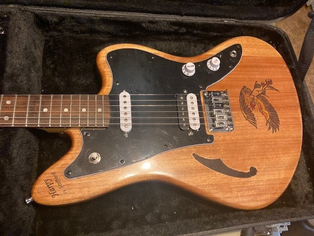 Transparent purple semi-hollow double-cutaway guitar with gold hardware, photographed in sunlight