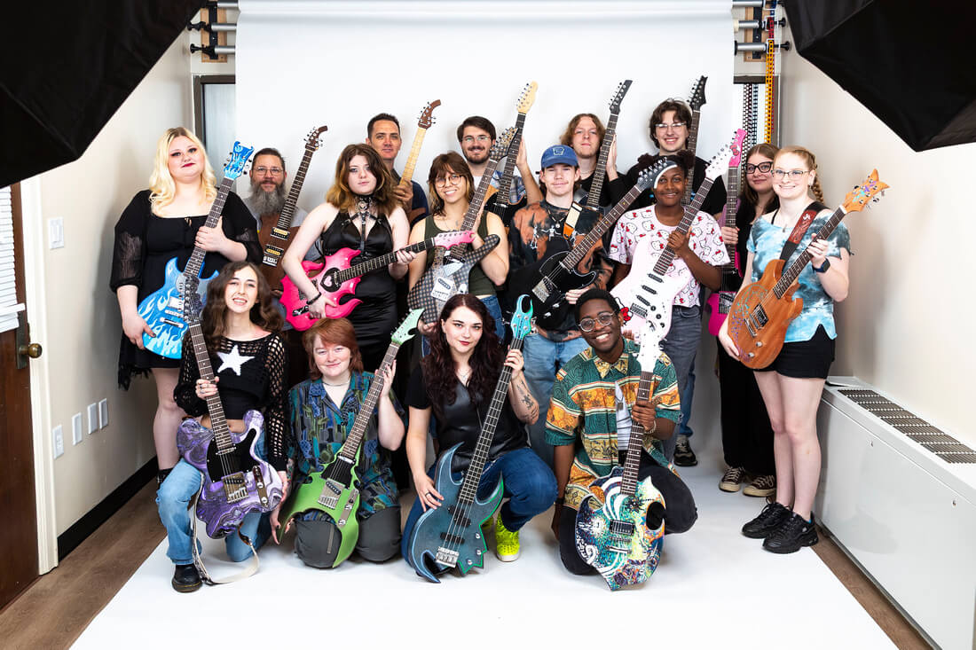 Southern Arkansas University students hold the custom electric guitars they designed, built, and finished in course ART 4073.