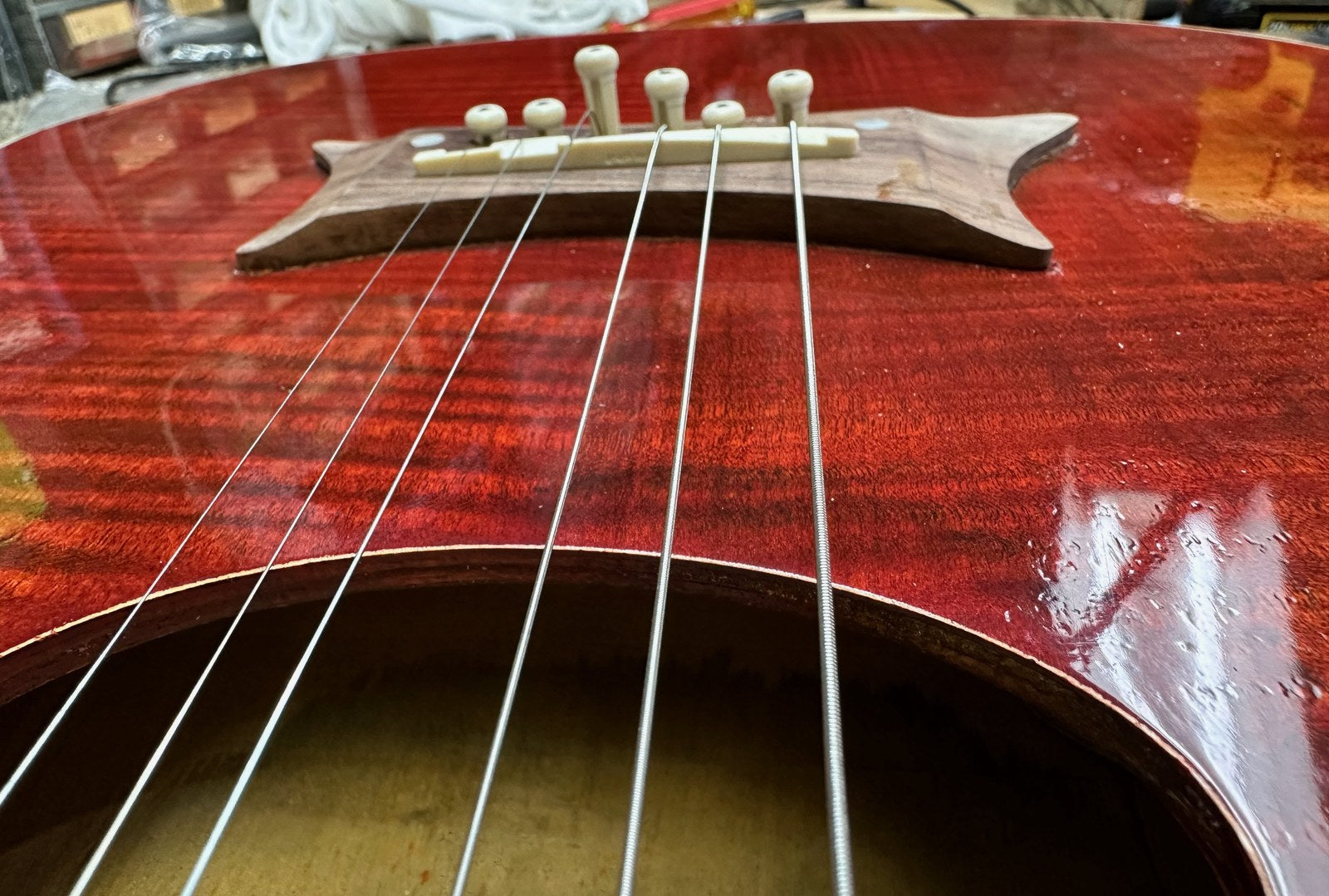 A finished acoustic-style bridge glued to the top with six white bridge pins seated and the guitar strung