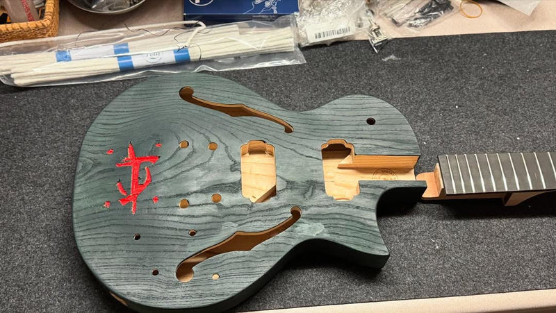 The same guitar body after green stain, with the carved rune filled in red