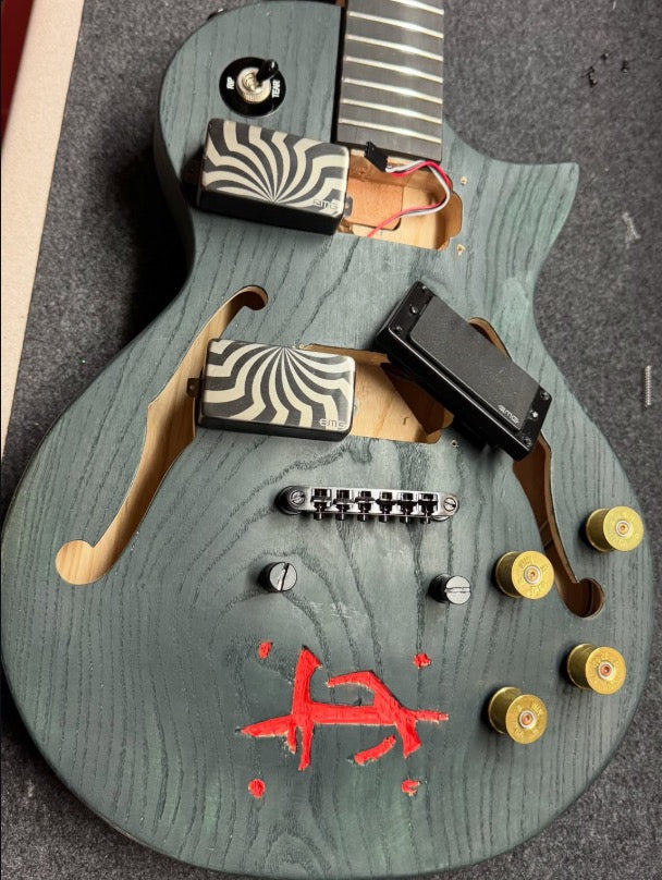 Guitar body during assembly with humbuckers, shotgun shell knobs and bridge fitted