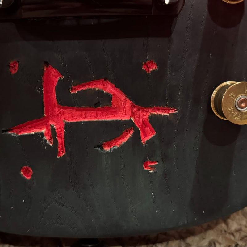 Close-up of the hand-carved rune filled with red paint next to a shotgun shell control knob