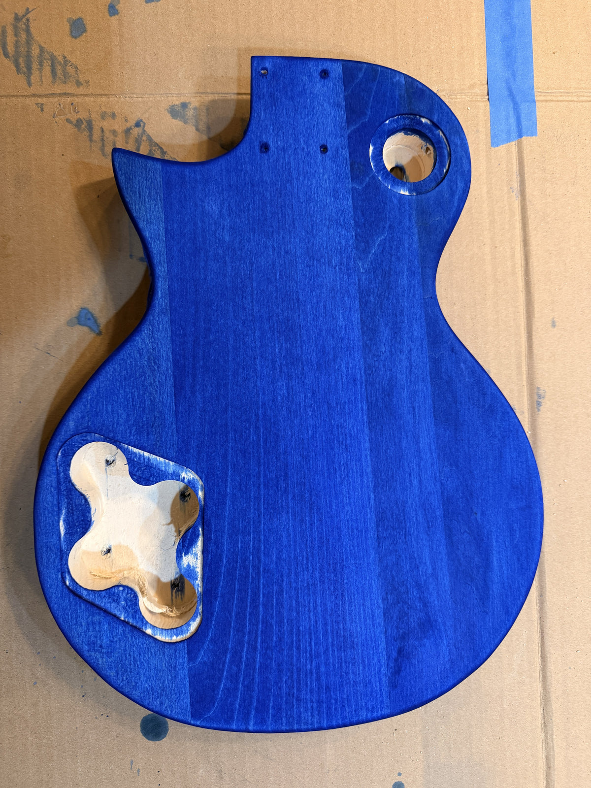 Back of the guitar body dyed solid blue, plain grain with no figure, neck pocket block still fitted