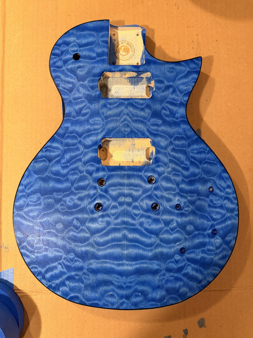Quilted maple top dyed bright blue with the pickup cavities masked, laid on cardboard