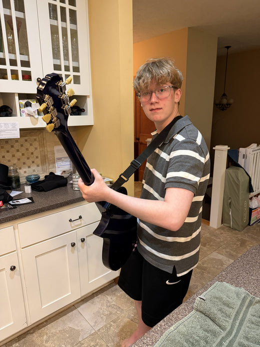 Builder holding the finished blue burst guitar with gold hardware