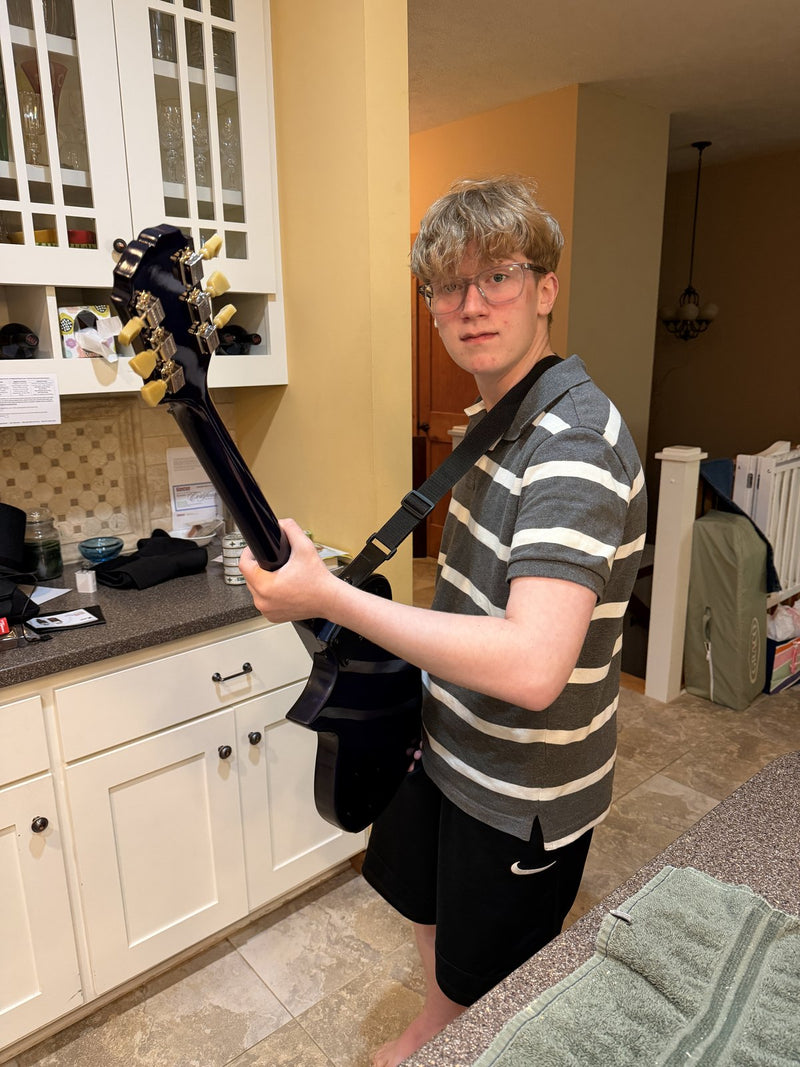 The same builder holding the finished blue burst guitar with gold hardware