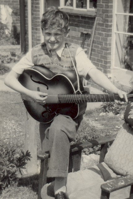 Byron Stafford as a boy in 1958, sitting in a garden playing his 1957 archtop guitar