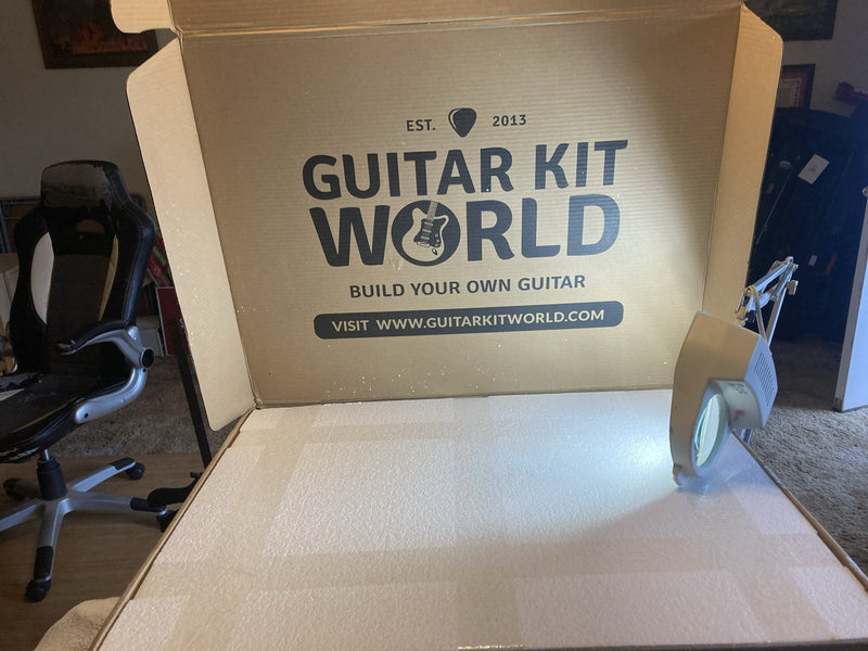 A Guitar Kit World shipping box with the lid folded open, contents still packed inside