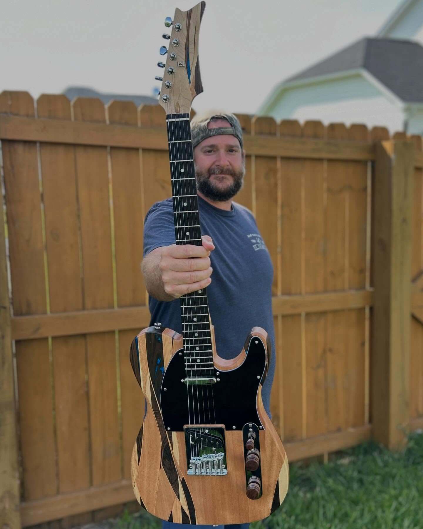 Builder holding a finished TE-style DIY guitar with a striped natural body