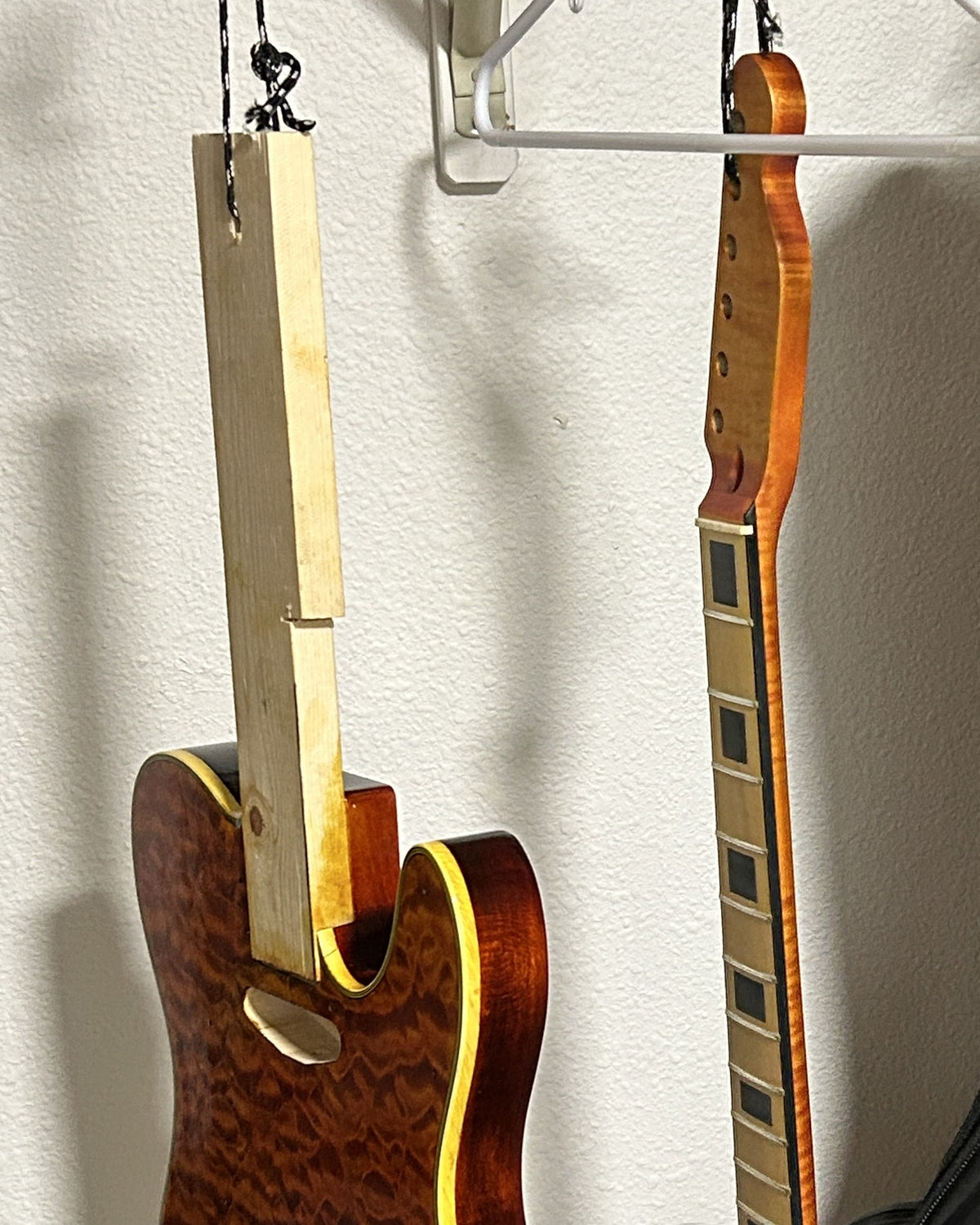 Guitar body hung from a pine strip and the maple neck hung by its headstock, drying between Tru-Oil coats