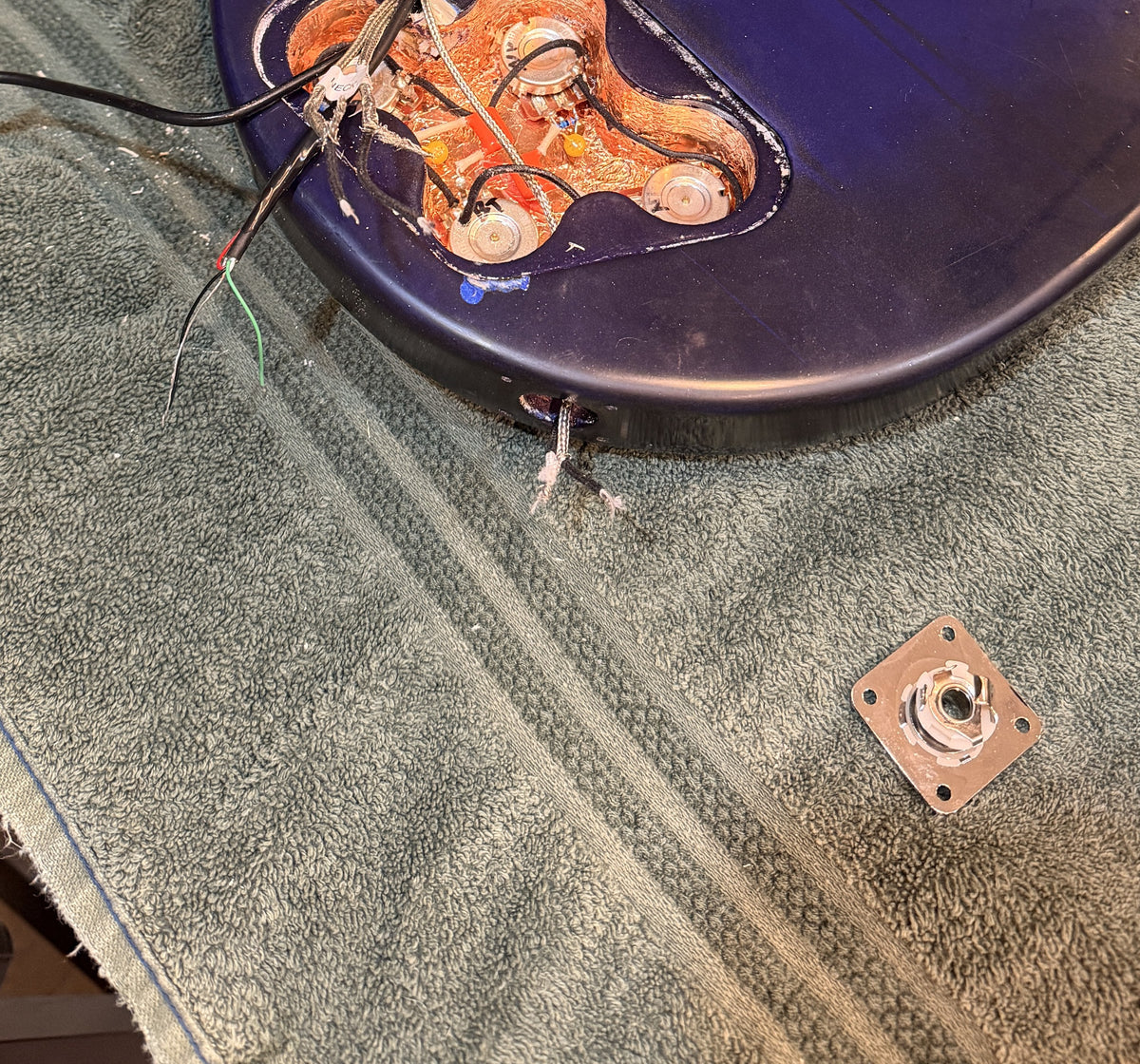 Copper shielded control cavity with four wired pots and labelled pickup leads, output jack plate beside the body