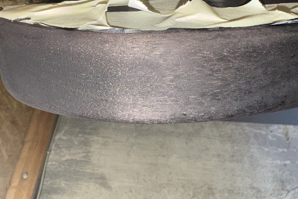 Close-up of a black stained bass body edge showing lighter unfilled grain pores in the mahogany