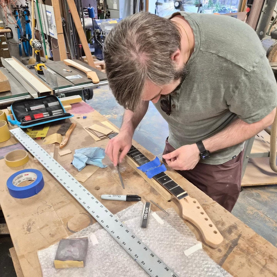 Filing and crowning frets on a maple neck at the Baltimore guitar building workshop