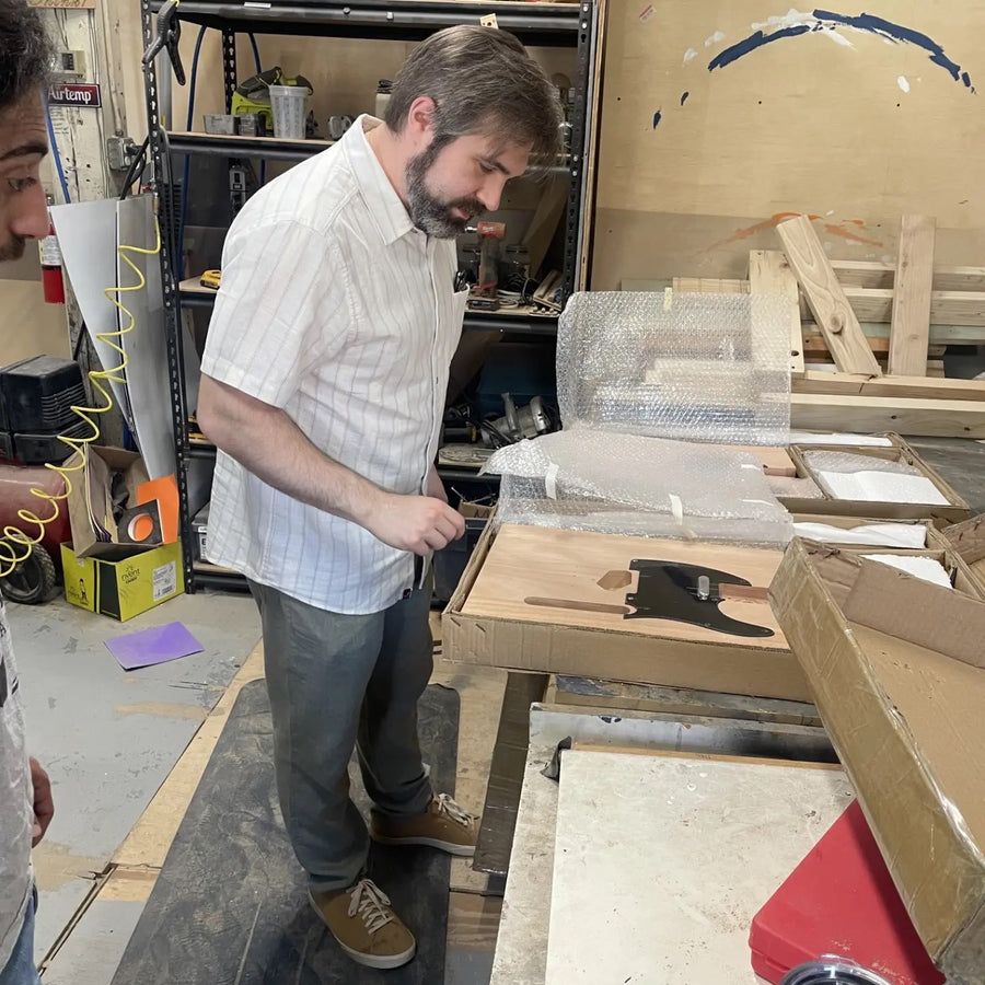 Two builders unpacking a T-style guitar kit at the Baltimore guitar building workshop