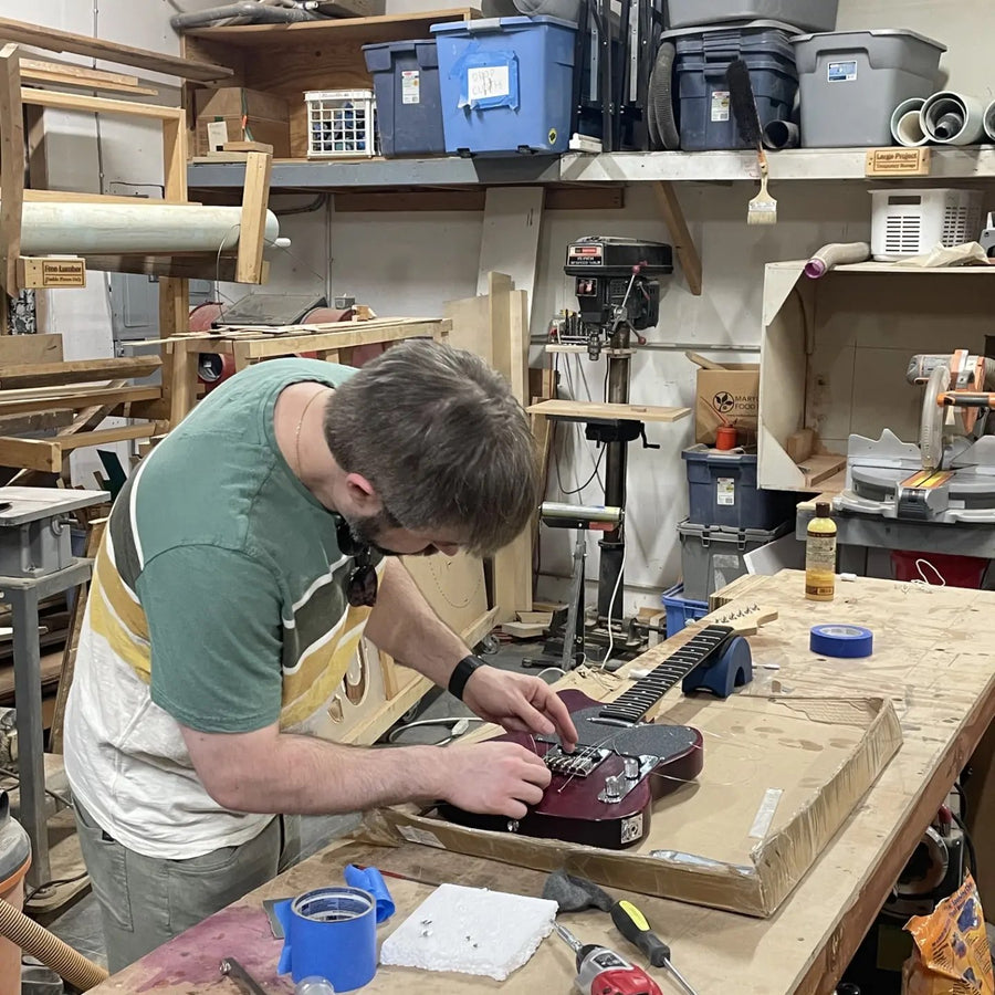 Stringing up a finished purple T-style electric guitar at the Baltimore guitar building workshop
