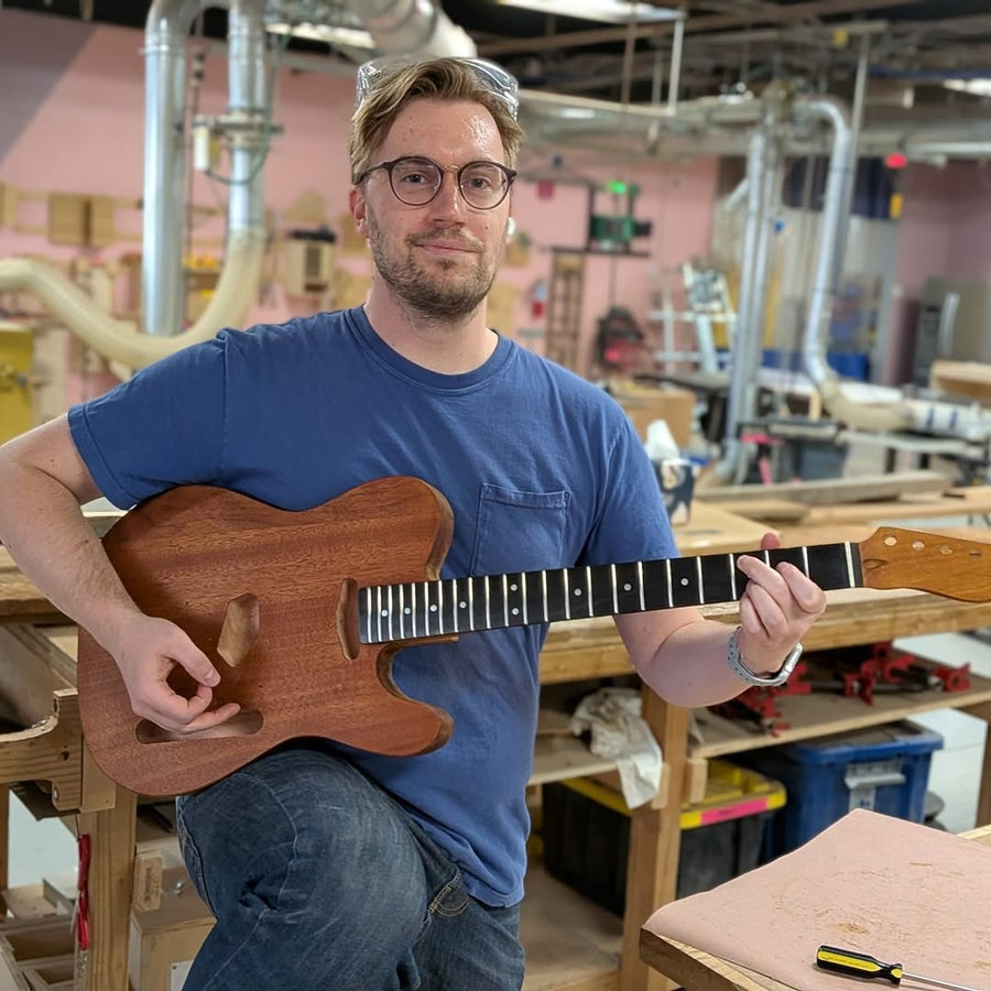 Builder holding the electric guitar they completed at the Fairfax guitar building workshop