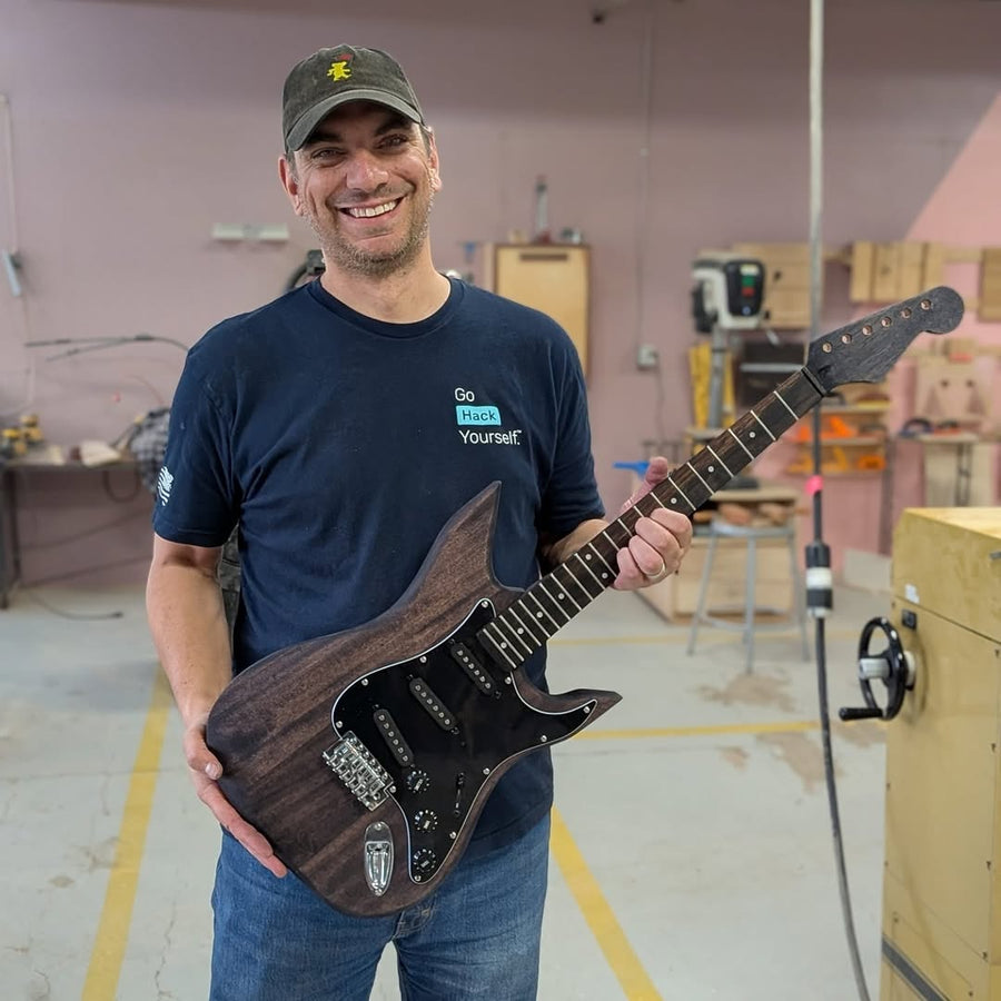Builder with the finished guitar they built at the Fairfax guitar building workshop