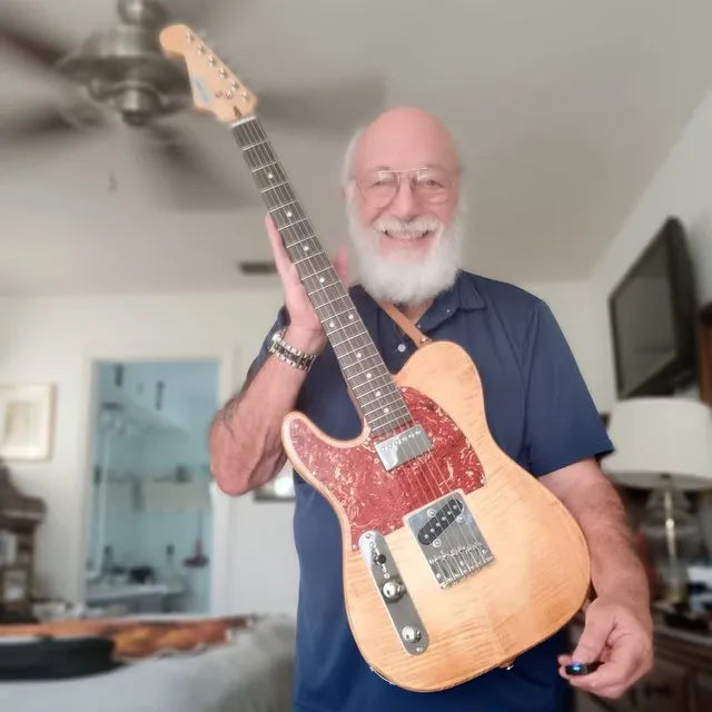 Peter holding a T-style guitar with a flame-maple top and red pearl pickguard he built from a GKW kit